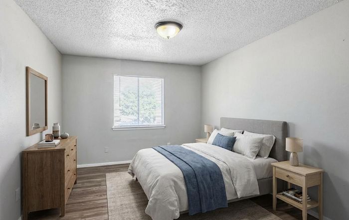 Bright and inviting bedroom featuring a cozy bed with plush linens, elegant wooden furniture, and abundant natural light through a large window.