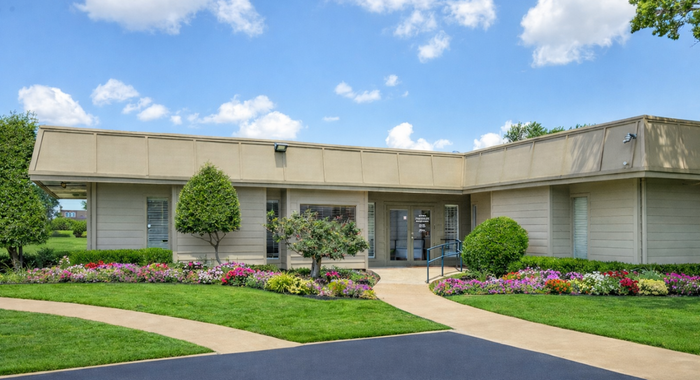 Inviting single-story building with manicured gardens and vibrant flowers under a bright blue sky.