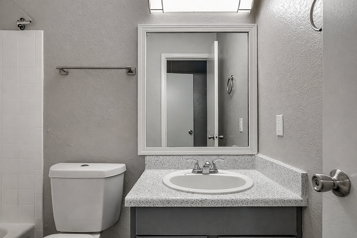 Modern bathroom with sleek fixtures, featuring a pristine countertop and spacious mirror, reflecting elegance and style.