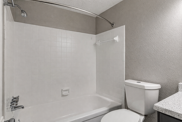 Modern bathroom with elegant white bathtub, sleek tile walls, and a contemporary countertop for a fresh and inviting space.