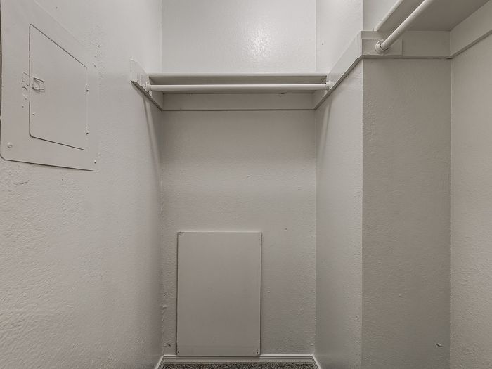 Spacious walk-in closet with ample shelving and clean white walls, perfect for organizing and maximizing storage.