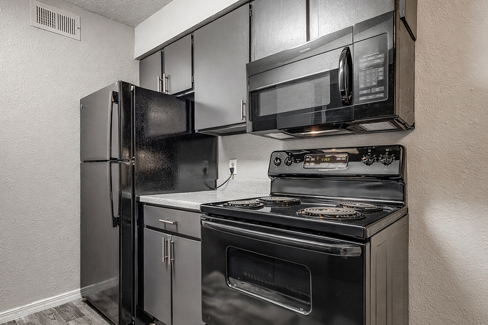 Modern kitchen with sleek black appliances, elegant cabinetry, and stylish gray countertops.