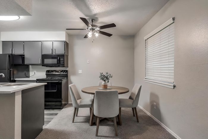 Modern kitchen and dining area featuring sleek dark cabinets, stylish round table, and cozy seating.