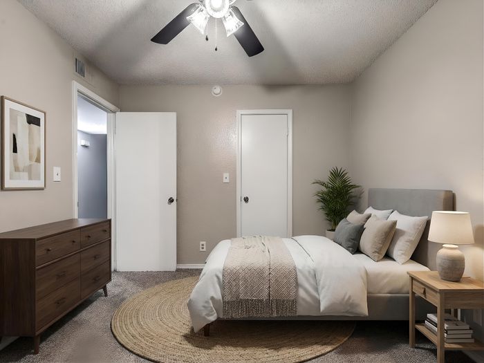 Elegant bedroom with a cozy bed, modern dresser, and stylish decor, featuring a ceiling fan and ambient lighting for ultimate relaxation.