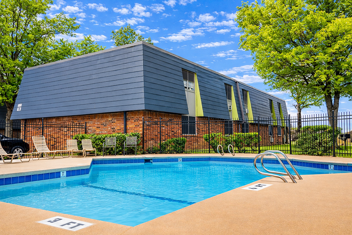Charming apartment with modern design features a refreshing outdoor pool, surrounded by lush greenery and a fenced patio area perfect for relaxation.
