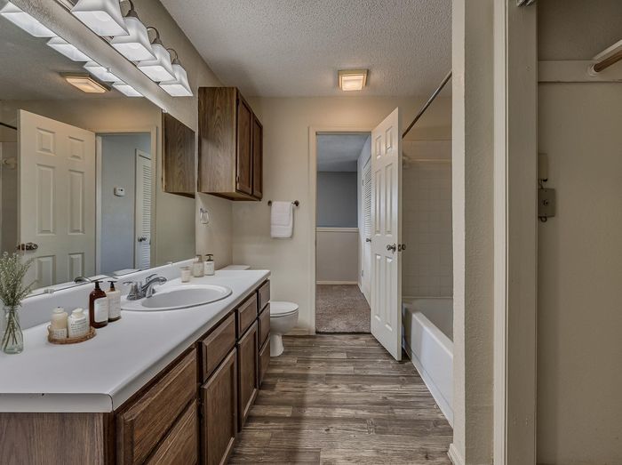 Elegant bathroom with wooden cabinets, sleek countertop, and modern lighting, offering a warm and inviting ambiance.