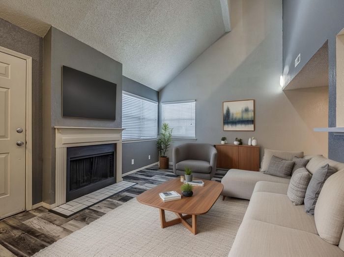 Inviting living room with modern decor, featuring a cozy fireplace, sleek furniture, and abundant natural light.
