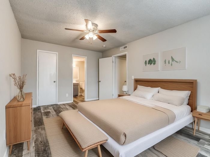 Bright and inviting bedroom with modern decor, featuring a cozy bed, stylish artwork, and elegant wooden furniture.
