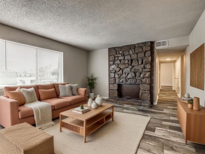 Inviting living room with a cozy peach sofa, rustic stone fireplace, and modern wooden furnishings, ideal for relaxation.