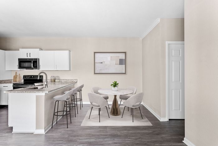 Modern apartment kitchen with sleek white cabinetry, granite countertops, and stylish open dining area with elegant decor.