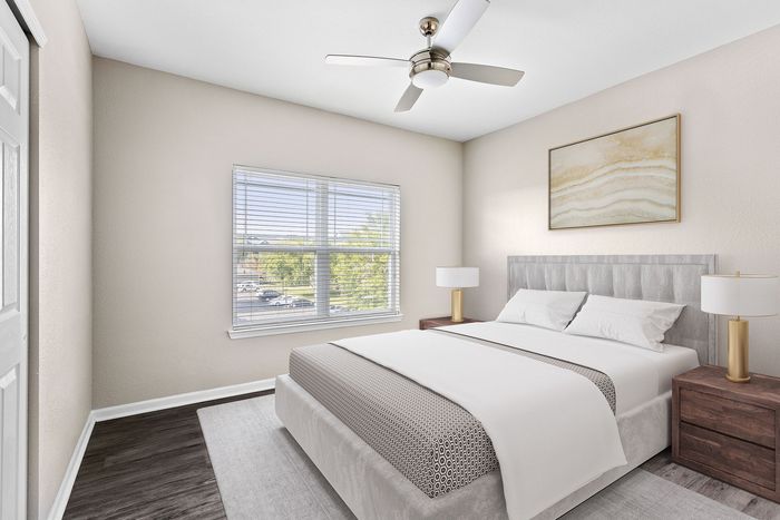 Bright and airy bedroom featuring a cozy bed, elegant side tables, and a ceiling fan, illuminated by natural light through a large window.