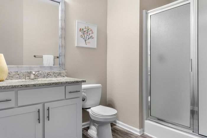 Chic bathroom with elegant granite countertop, modern shower, and vibrant wall art, perfect for relaxing decor.