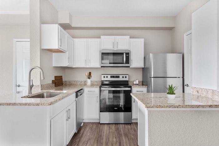 Modern kitchen with sleek stainless steel appliances, elegant granite countertops, and stylish white cabinetry.