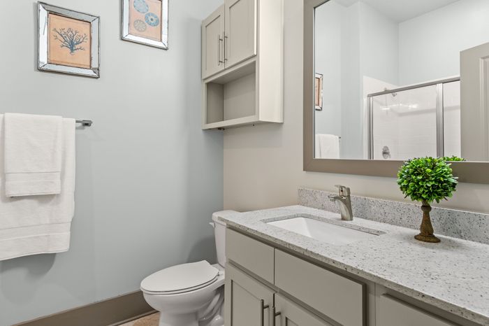 Elegant bathroom with stylish granite countertop, framed mirror, and decorative artwork, offering a modern and fresh ambiance.