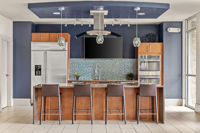 Elegant modern kitchen with sleek stainless steel appliances, chic blue backsplash, and a spacious island with stylish bar seating.