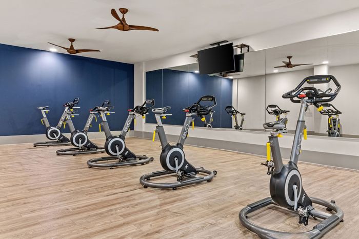 Contemporary fitness center with sleek exercise bikes, mirrored walls, and wooden floors, perfect for energizing workouts.