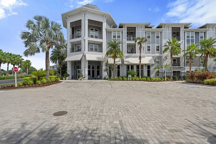 Elegant apartment complex showcasing modern architecture with lush palm trees and a welcoming entrance.