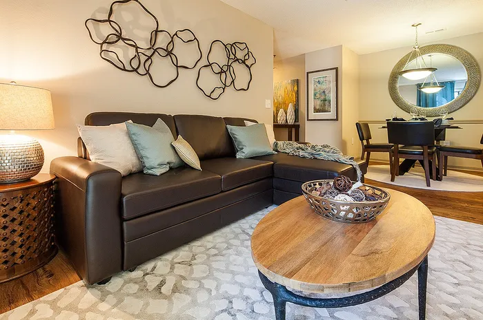 Chic living room with a plush leather sofa, stylish wall art, and elegant dining area, perfect for modern comfort.