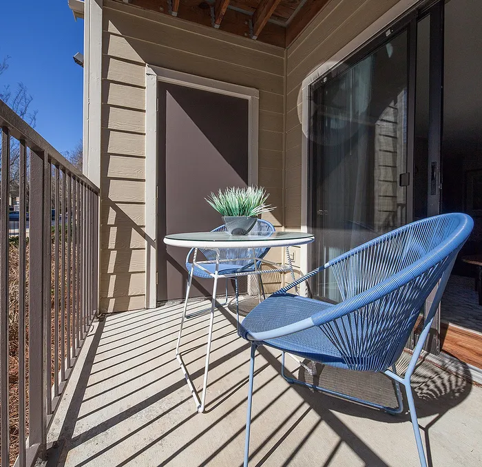 Charming balcony with modern blue chairs and small table, perfect for outdoor relaxation.