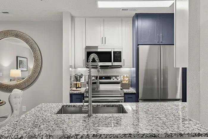 Modern kitchen with sleek stainless steel appliances, elegant granite countertops, and stylish cabinetry, featuring a chic round mirror accent.