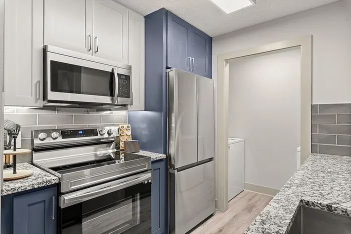 Modern kitchen with sleek stainless steel appliances, elegant granite countertops, and crisp cabinetry in a stylish apartment setting.