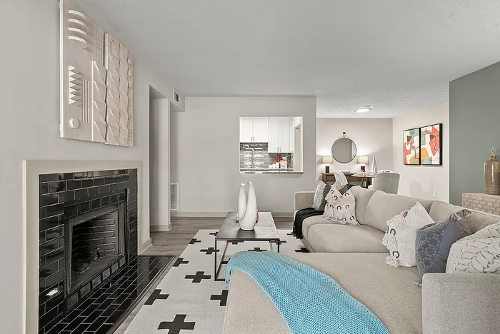 Elegant living room with a cozy fireplace, stylish sofa, and chic modern decor. Open view to a sleek kitchen and dining area, perfect for relaxation and entertaining guests.