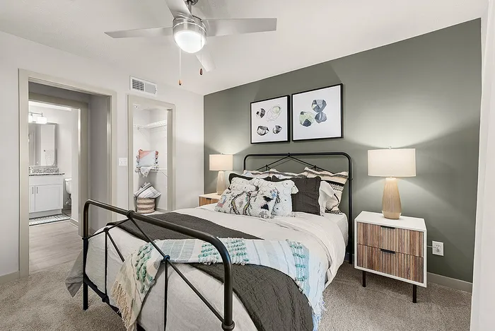 Modern bedroom with a cozy bed, stylish decor, bedside lamps, and a spacious walk-in closet leading to an elegant bathroom.