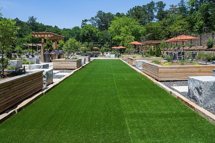 Charming outdoor recreation area featuring a lush green lawn, stylish pergolas, and inviting seating spaces with vibrant umbrellas.