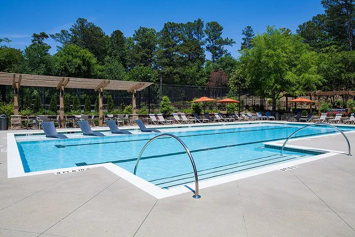 Inviting outdoor pool area with sun loungers, vibrant umbrellas, and lush greenery, perfect for relaxation and leisure.