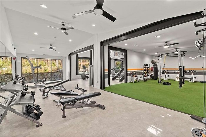 Modern fitness center with state-of-the-art gym equipment, bright open spaces, and sleek design. Features free weights, cardio machines, and a functional training area with artificial turf.