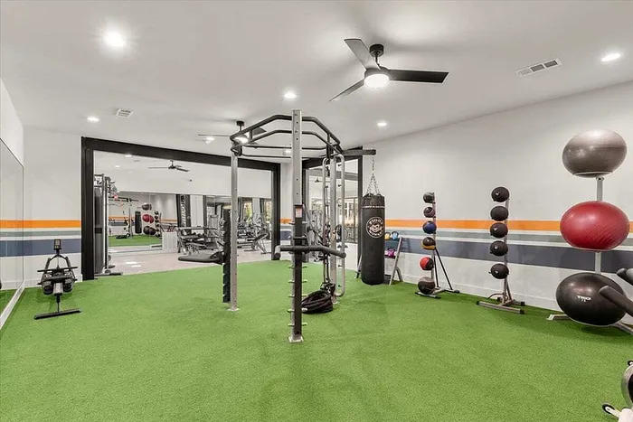 Modern and spacious fitness center with state-of-the-art equipment, lush green flooring, and vibrant accents, perfect for an energizing workout experience.