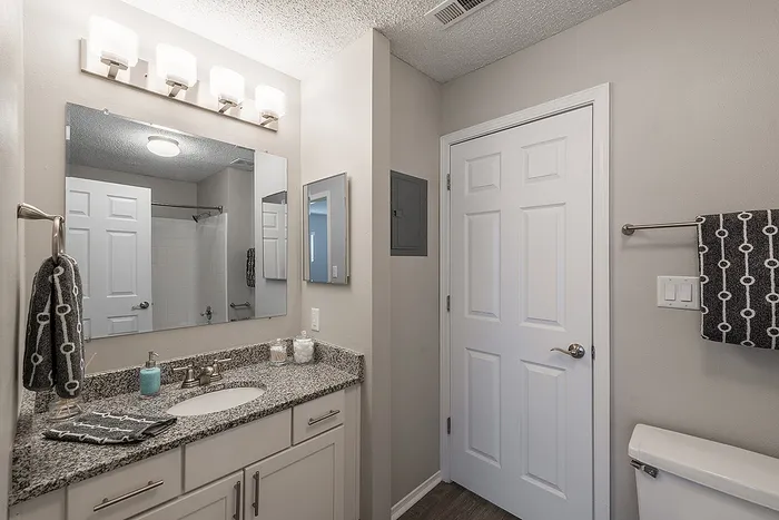 Modern bathroom with granite countertop, stylish lighting, and elegant fixtures, offering a clean and inviting space.