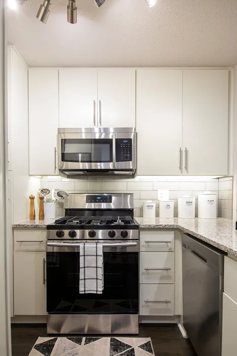 Modern kitchen with sleek stainless steel appliances, elegant white cabinetry, and stylish granite countertops.