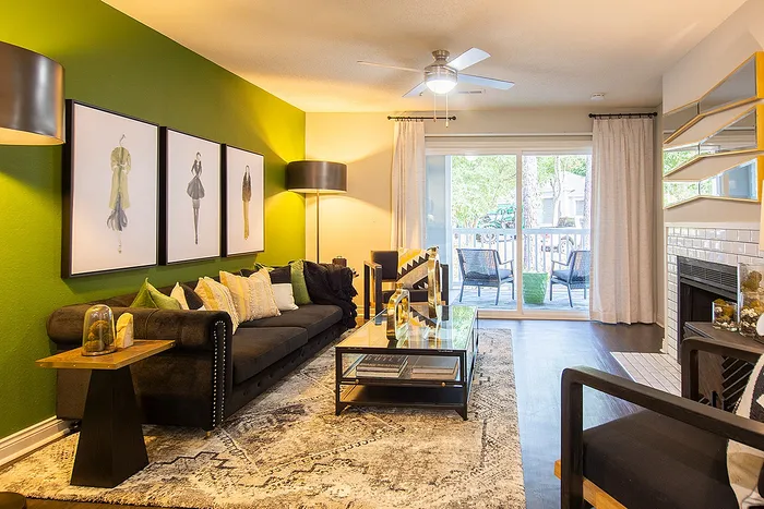 Vibrant living room with stylish decor, featuring a bold green accent wall, contemporary artwork, and a cozy seating area opening to a serene balcony view.
