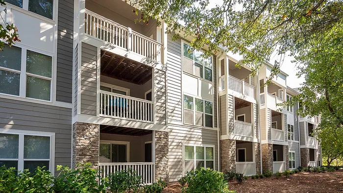 Charming modern apartment building with elegant balconies surrounded by lush greenery, perfect for tranquil living.