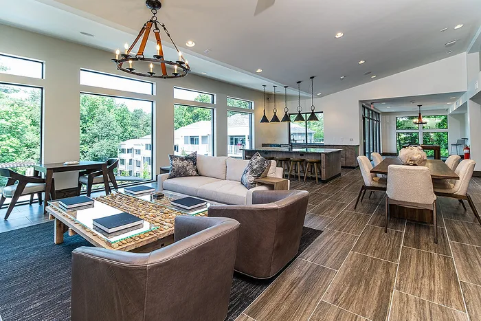 Inviting open-concept living room with stylish leather chairs, modern sofa, and expansive windows offering scenic views, adjacent to a chic dining area and contemporary kitchen.