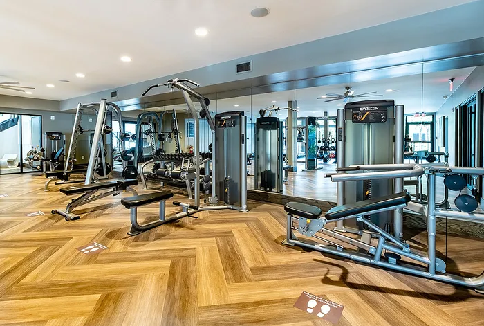 Luxurious gym facility with state-of-the-art fitness equipment and elegant hardwood flooring.