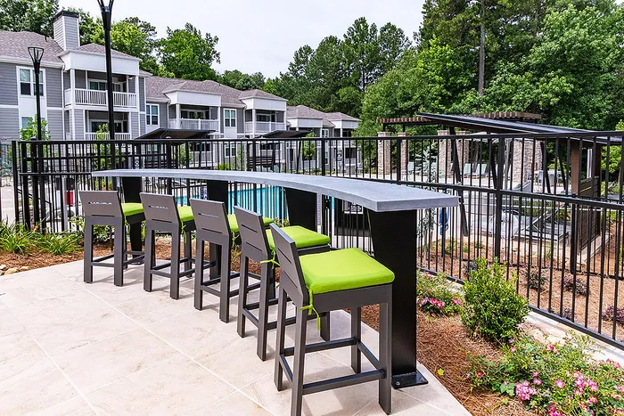 Chic outdoor seating area overlooking a pristine pool, perfect for relaxation and entertainment in a lush residential complex.