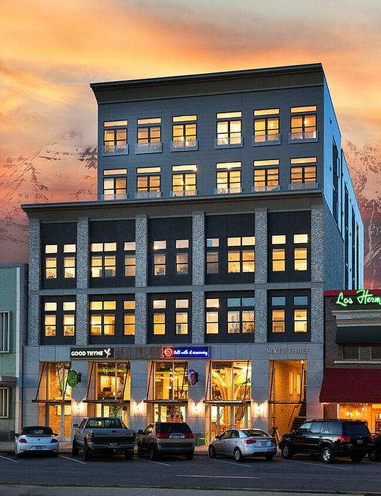 Chic multi-story apartment building with illuminated windows at sunset.