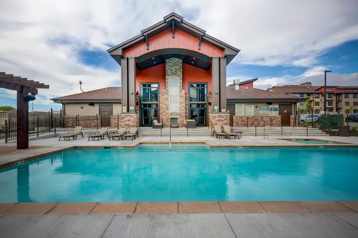 Luxurious apartment complex with a stunning outdoor pool, modern architecture, and inviting lounge chairs for relaxation.