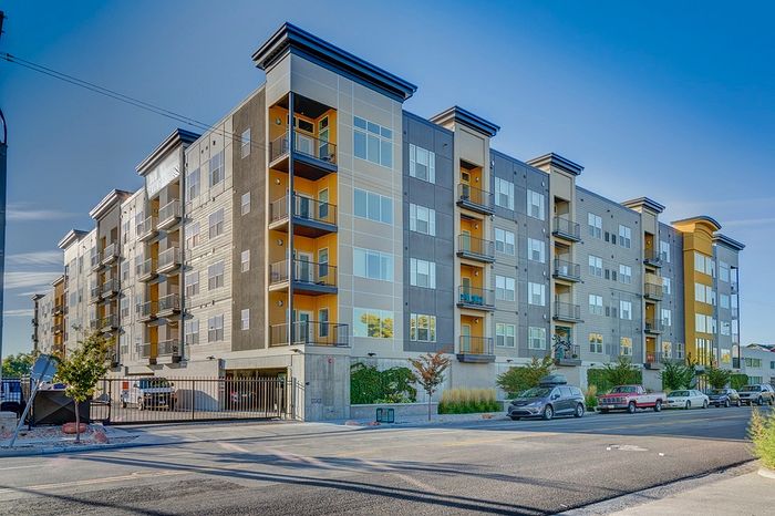 Modern urban apartment complex with stylish design, featuring multiple balconies and a secure gated entry.