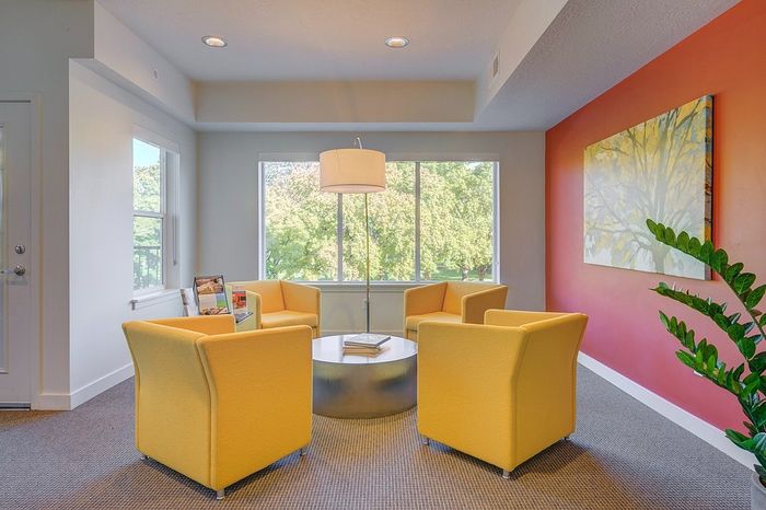Bright and inviting sitting area with modern yellow chairs, large windows showcasing a scenic view, and elegant decor.