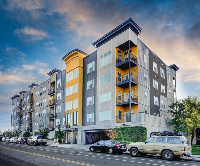 Modern multi-story apartment building with vibrant yellow accents, offering spacious living spaces and a stylish urban design.