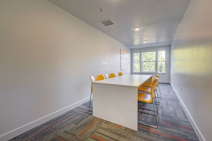Millcreek UT Apartments with In-Unit Washer and Dryer - VIA - Spacious Conference room with Large Table, Surrounded by Chairs, Large Windows and Overhead Lighting.