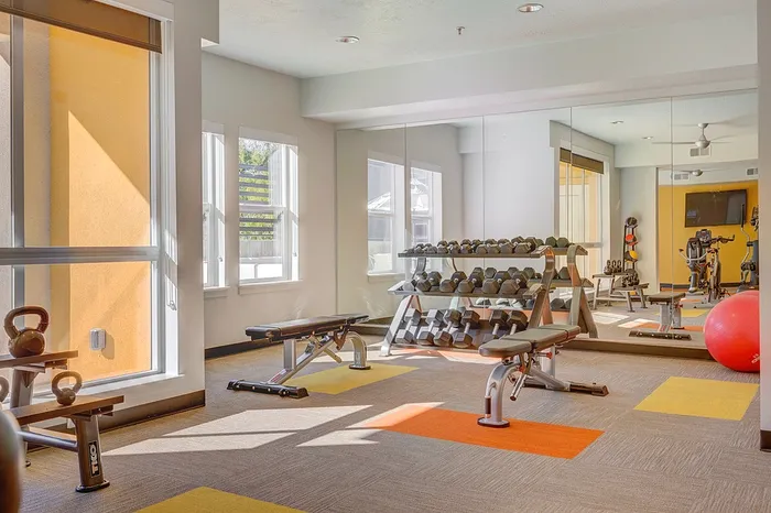Bright and inviting fitness center with modern equipment, mirrored walls, and vibrant flooring for an energizing workout experience.
