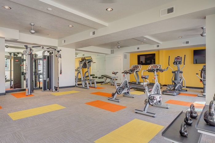 Modern fitness center with state-of-the-art exercise equipment, vibrant decor, and spacious workout area.