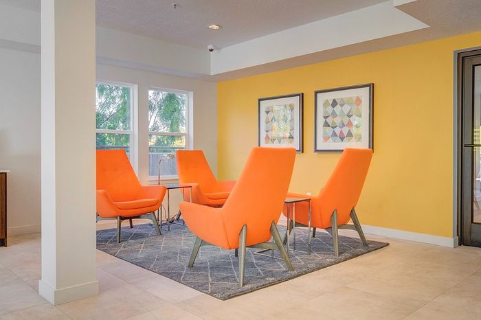Inviting lounge area with vibrant orange chairs, stylish geometric artwork, and natural lighting.
