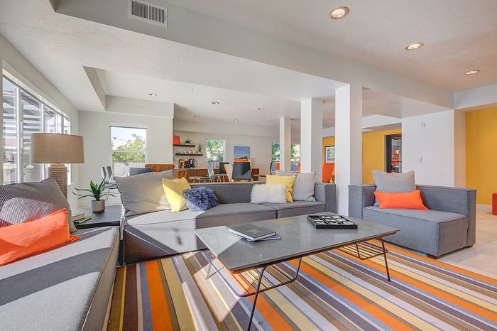 Bright and modern living room with stylish gray sofas, colorful accent pillows, and sleek coffee table, featuring large windows and open layout for natural light.
