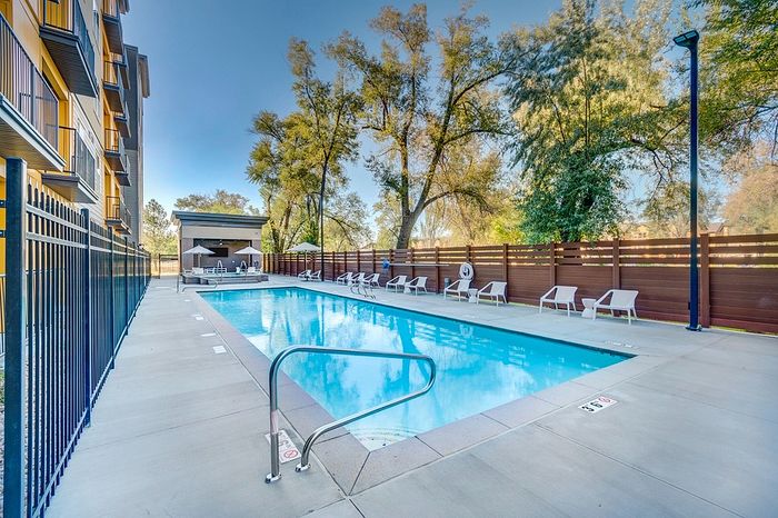 Apartments near Harmony Park Millcreek, UT - VIA - Fenced in Sparkling Swimming Pool, Poolside Seating, and Spa Surrounded by Lush Trees