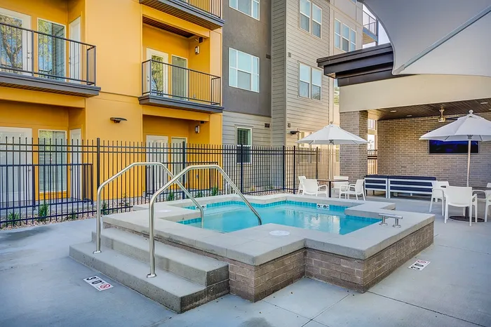 Modern apartment courtyard featuring a luxurious spa pool, stylish seating area, and vibrant exterior design.